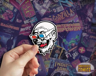 May include: A white sticker with a melting skull wearing 3D glasses. The skull is grinning and has a dripping tongue. The sticker is on a background of comic book covers.