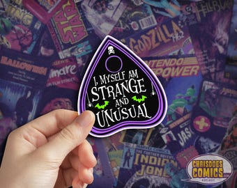 May include: A black and purple Ouija board sticker with the text "I, Myself Am Strange and Unusual." The sticker features a skull, spider, and bat graphics. The background is a collage of comic book covers.