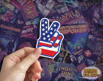 May include: A peace sign sticker with the American flag design. The sticker is red, white, and blue and has a white outline.