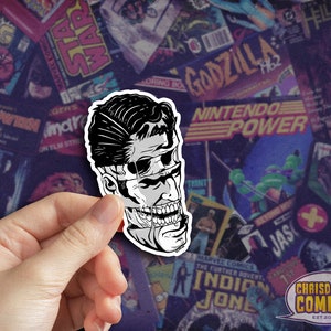 May include: Black and white illustration of a man's face with a skull-like jawline. The illustration is printed on a sticker.