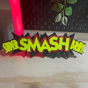 May include: A black, red, and yellow 3D sign that reads "SUPER SMASH BROS." The sign has a jagged, comic book style border.