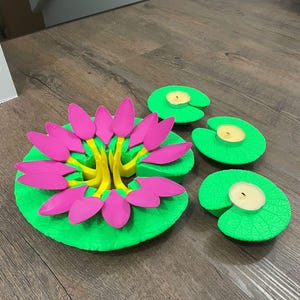 May include: A set of three green and yellow lily pad candle holders. The center lily pad has a pink flower with yellow stems.