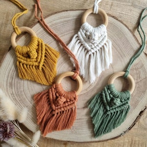 Op de afbeelding: Vier macramé wandhangers met houten ringen. De hangers zijn in tinten geel, wit, oranje en groen.