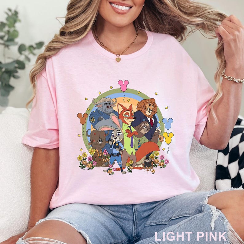 Puede incluir: Camiseta rosa claro con un dise&ntilde;o gr&aacute;fico colorido de personajes de animales, flores y globos de Mickey Mouse. El texto "LIGHT PINK" est&aacute; en la parte inferior. La camiseta tiene cuello redondo y mangas cortas.