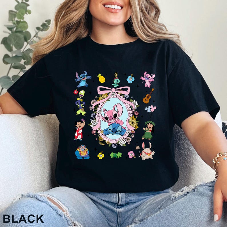 May include: Black t-shirt with a colourful graphic of Stitch and Angel characters, surrounded by floral and tropical elements. The design includes a central oval frame with the characters, and smaller illustrations around the frame. The word "BLACK" is printed at the bottom.