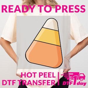 Peut inclure: Un t-shirt blanc avec un motif de bonbon de maïs orange, jaune et blanc, avec des contours noirs. Les mots "READY TO PRESS", "HOT PEEL" et "DTF TRANSFER" sont imprimés sur le t-shirt. Il y a aussi un graphique DTF 1 jour.