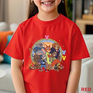 Puede incluir: Una camiseta roja con un estampado de personajes de la pel&iacute;cula "Zootr&oacute;polis". El dise&ntilde;o incluye a Judy Hopps, Nick Wilde y otros personajes animales, rodeados de flores y un arco&iacute;ris. La palabra "RED" est&aacute; impresa en la parte inferior.