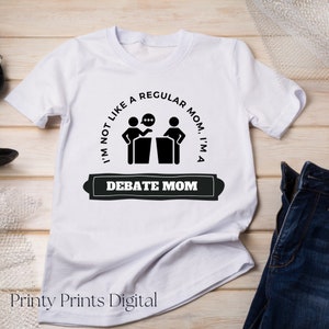 Pode incluir: Camiseta branca com um gráfico preto de duas pessoas em pódios com balões de fala. O texto diz "Eu não sou como uma mãe normal, eu sou uma mãe de debate."