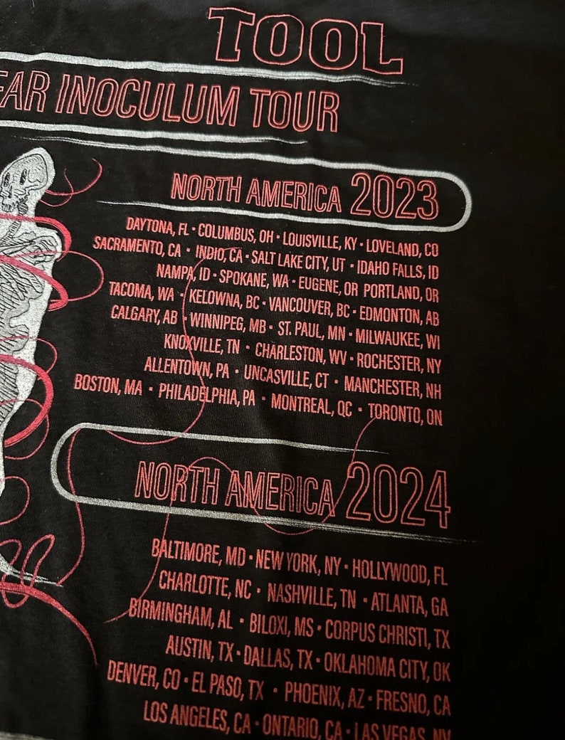 May include: Black t-shirt with white text that reads "TOOL EAR INOCULUM TOUR" and lists tour dates for North America in 2023 and 2024.