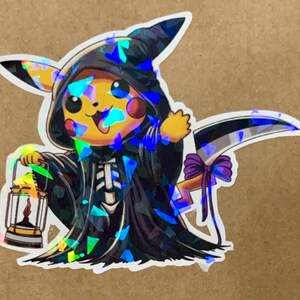May include: A holographic sticker of a yellow Pikachu dressed as the Grim Reaper, holding a lantern and a scythe. The sticker has a black background with a rainbow iridescent effect.
