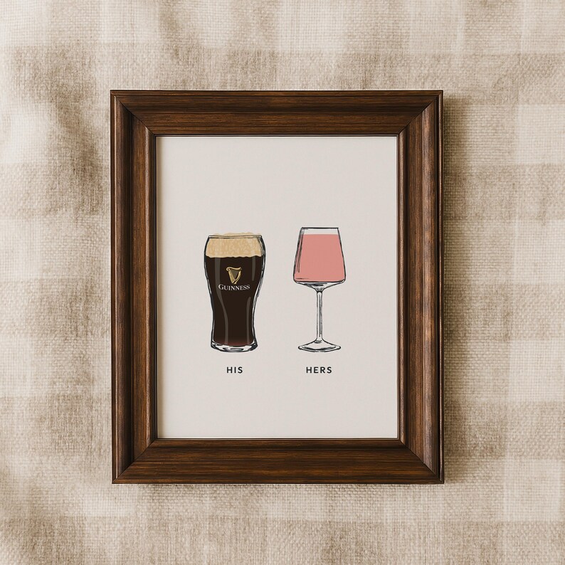 May include: A framed print featuring two illustrated glasses: a pint of Guinness and a pink wine glass. The words "HIS" and "HERS" are printed below the glasses. The frame is dark brown.
