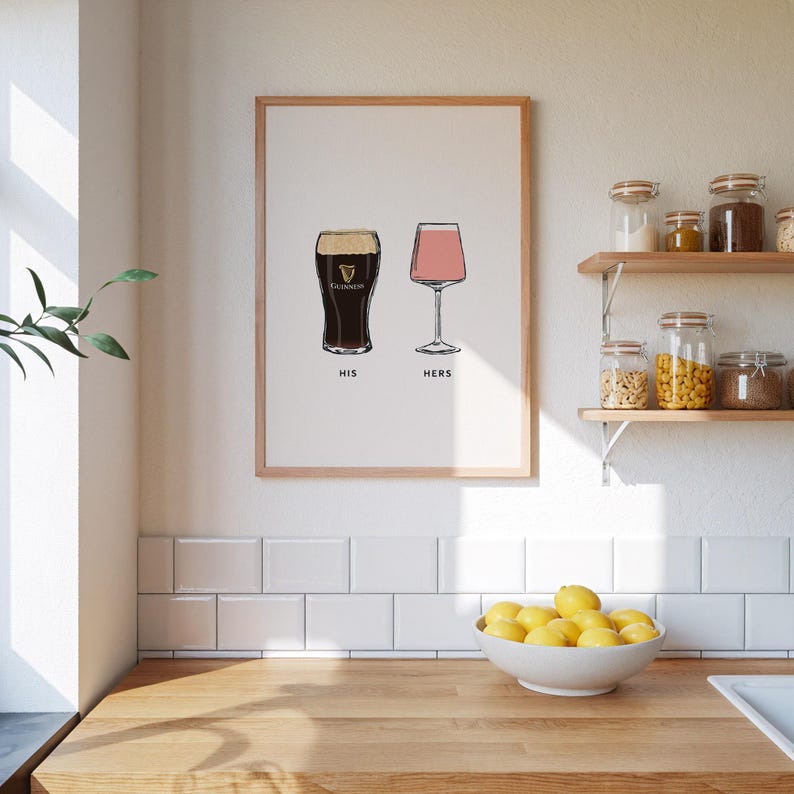 May include: A framed print featuring illustrations of a pint of Guinness and a pink wine glass. The text "HIS" and "HERS" is below the glasses. The print is in a light wood frame.