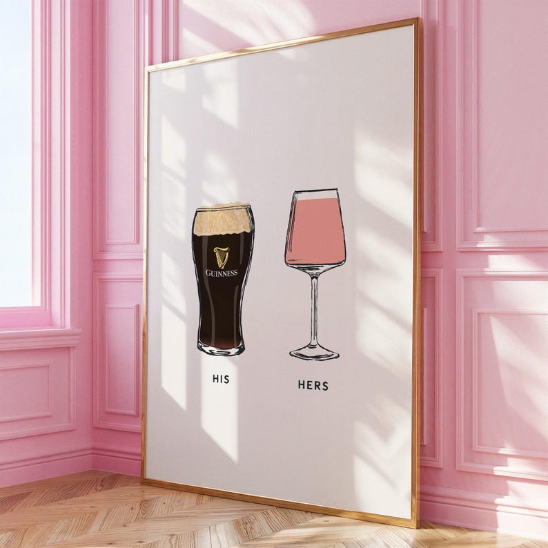 May include: A framed art print featuring two sketched drink glasses. One is a dark stout with the Guinness logo, labeled "HIS." The other is a pink drink in a stemmed glass, labeled "HERS." The artwork has a minimalist style with black outlines.