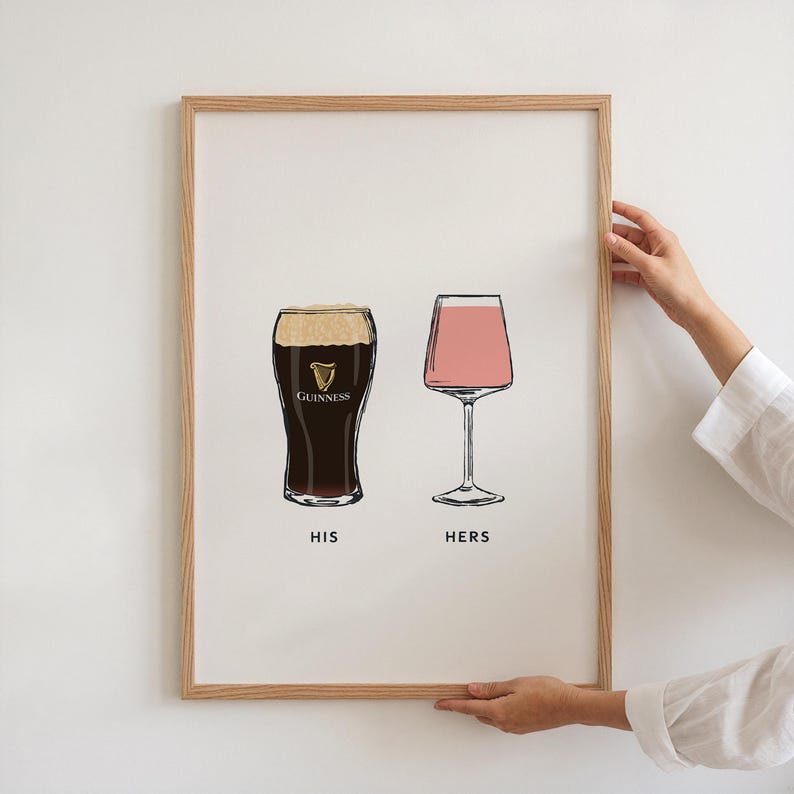 May include: A framed print featuring two illustrated glasses: a Guinness pint and a pink cocktail glass. The text "HIS" and "HERS" are below the glasses. The print is in a light wood frame.