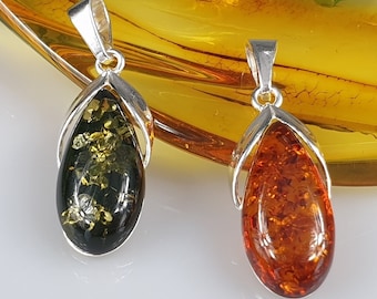 May include: Two teardrop-shaped amber pendants with silver bail settings. The pendant on the left is a dark green amber with gold flecks. The pendant on the right is a light amber with a reddish hue.