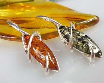 May include: Two amber pendants with silver wire wrapping. One pendant is a dark green amber and the other is a light amber.