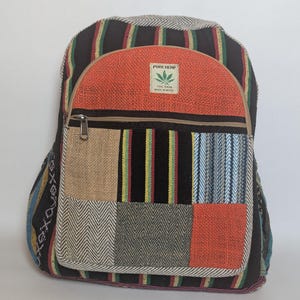 May include: A multi-coloured backpack with a patchwork design. The bag features a variety of fabrics, including striped and textured materials, with a prominent orange panel and a "PURE HEMP" label. It has a zipped main compartment and adjustable straps.