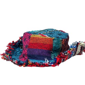 May include: A patchwork bucket hat featuring a variety of colourful fabrics, including teal, magenta, and striped patterns. The hat has a frayed, raw-edge brim and a flat top, with the text Himalayas Collectables printed in the upper left corner.