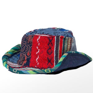 Può includere: Un cappello a secchiello con un design patchwork composto da vari motivi in tessuto nei colori rosso, blu, verde e nero. Il cappello presenta una tesa larga e flessibile e una corona arrotondata. Il testo "Himalayas Collectables" è in alto a sinistra.