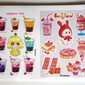 May include: A sheet of stickers featuring bubble tea and berry-themed desserts. The bubble tea stickers show different flavours like strawberry, peach, mango, watermelon, grape, dragon fruit, and cherry. The berry-themed stickers include a bunny wearing a strawberry hat, a strawberry cake, a strawberry sundae, and a strawberry cupcake.