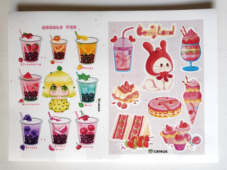 May include: A sheet of stickers featuring bubble tea and berry-themed desserts. The bubble tea stickers show different flavours like strawberry, peach, mango, watermelon, grape, dragon fruit, and cherry. The berry-themed stickers include a bunny wearing a strawberry hat, a strawberry cake, a strawberry sundae, and a strawberry cupcake.