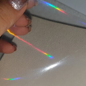 Puede incluir: Una lámina de película holográfica iridiscente con colores arcoíris que se reflejan en la superficie.
