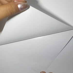 Puede incluir: Primer plano de una hoja de papel blanca que se est&aacute; despegando para revelar otra hoja de papel blanca debajo.