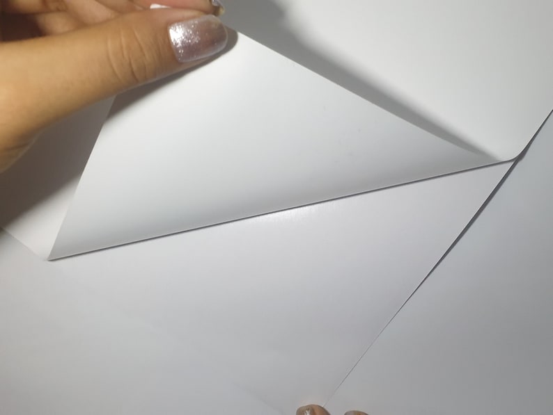 Puede incluir: Primer plano de una hoja de papel blanca que se est&aacute; despegando para revelar otra hoja de papel blanca debajo.