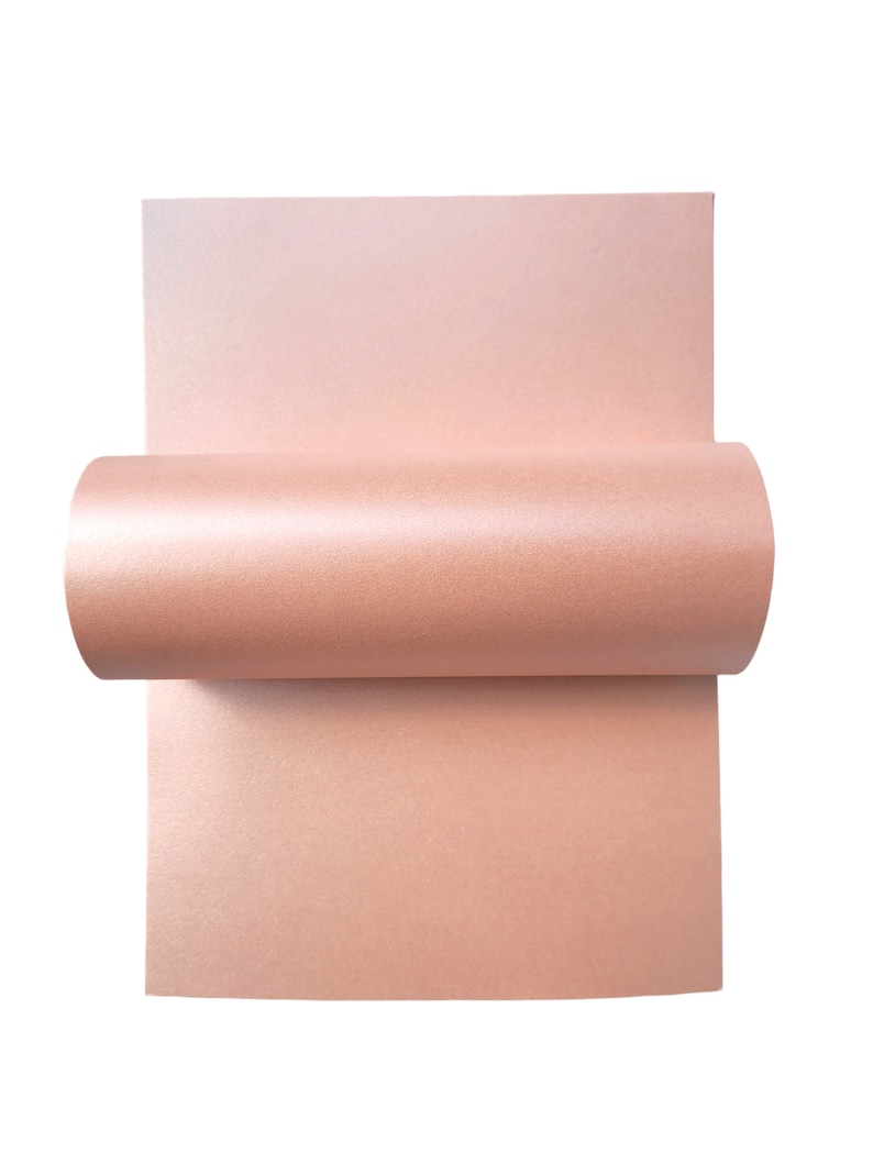 Op de afbeelding: Een vel lichtroze metallic papier opgerold. Het papier heeft een subtiele glans.