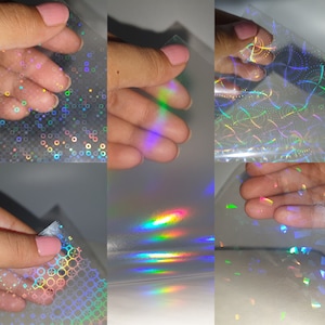 May include: Four sheets of iridescent holographic vinyl with different patterns. The vinyl is clear with a rainbow sheen. The patterns include circles, lines, and squares.