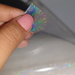 May include: A sheet of iridescent holographic film with a rainbow pattern. The film is translucent and has a subtle shimmer.
