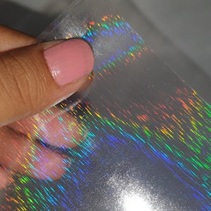 May include: A sheet of iridescent holographic film with a rainbow pattern. The film is translucent and has a subtle shimmer.