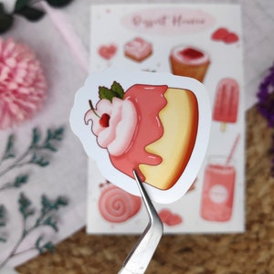 May include: A pink and yellow sticker with a cartoon illustration of a cake with pink frosting and a cherry on top. The sticker is part of a set of stickers with a "Sweet House" theme.