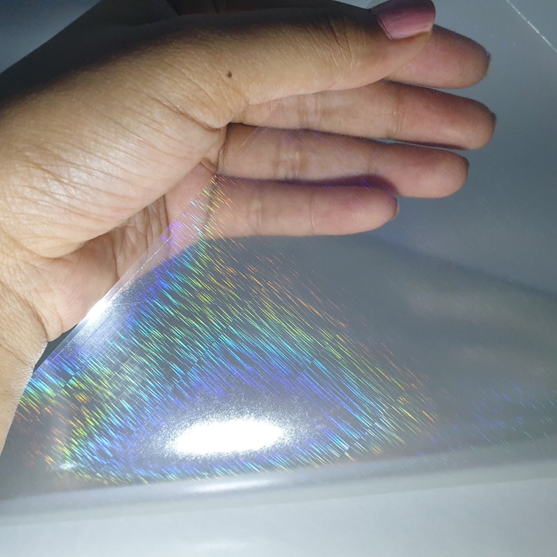 May include: A sheet of iridescent holographic film with a rainbow sheen. The film is translucent and has a subtle texture.