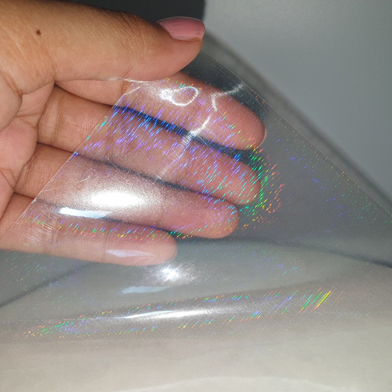 May include: A sheet of iridescent holographic vinyl with a rainbow sheen. The vinyl is clear and has a subtle texture.
