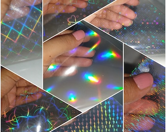 May include: Assortment of iridescent holographic sheets with various patterns, including a grid, hearts, and circles. The sheets are translucent and shimmer with rainbow colors.