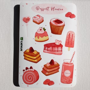 May include: A sheet of pink and white stickers featuring various desserts, including cakes, cupcakes, popsicles, and a milkshake. The stickers are decorated with hearts, sprinkles, and a bear. The text "Dessert Heaven" is at the top of the sheet.