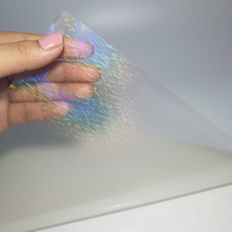 May include: A sheet of iridescent holographic film with a rainbow sheen. The film is translucent and has a subtle texture.