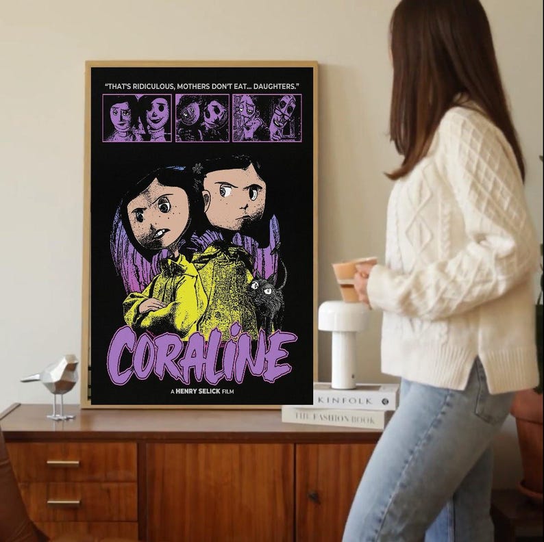 May include: A framed movie poster for "Coraline" with a black background and illustrations of characters and the film's title in purple. The poster includes the text "THAT'S RIDICULOUS, MOTHERS DON'T EAT... DAUGHTERS." and "A HENRY SELICK FILM."