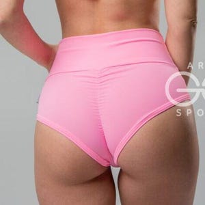 May include: Pink high-waisted athletic shorts. The shorts are a solid, vibrant pink color. The back of the shorts features a ruched design. The shorts are made of a smooth, stretchy material. The shorts are designed for athletic activities.