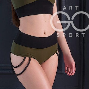 Puede incluir: Pantalones cortos deportivos verde oliva y negro con cintura alta y detalles recortados. Los pantalones cortos se combinan con un sujetador deportivo a juego. La imagen tiene el texto "ART GO SPORT" en blanco.