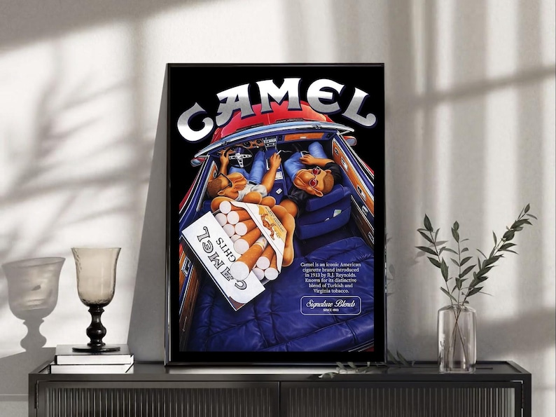Puede incluir: Un anuncio de Camel enmarcado que muestra el interior de un coche cl&aacute;sico con dos figuras y un paquete de cigarrillos. El logotipo de Camel est&aacute; en la parte superior. La imagen tiene un fondo negro y un marco negro.
