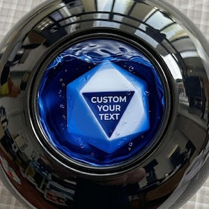 May include: A spherical fortune-telling toy with a polished, reflective black exterior. A circular window reveals a blue liquid containing a white, twenty-sided die. The die features a dark blue triangle with the white text CUSTOM YOUR TEXT.