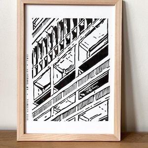 Peut inclure: Impression architecturale en noir et blanc d'une façade de bâtiment, encadrée dans du bois clair. L'impression présente une illustration détaillée d'un bâtiment avec des formes et des lignes géométriques. Le texte sur le côté gauche indique "CITE RADIEUSE - LE CORBUSIER - 1952".