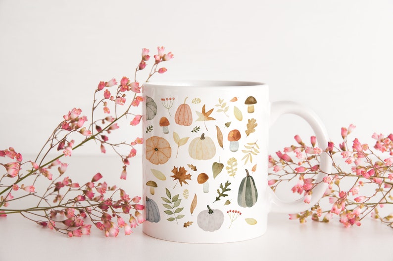 May include: White ceramic mug with a fall-themed design. The mug features a pattern of pumpkins, leaves, mushrooms, and acorns in shades of orange, brown, green, and gray.