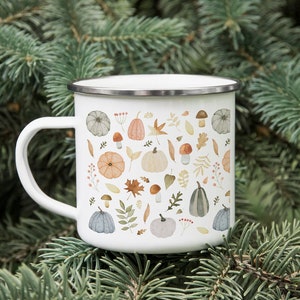 May include: White enamel mug with a pattern of fall leaves, pumpkins, and mushrooms. The mug has a silver rim and handle.