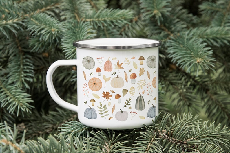 May include: White enamel mug with a pattern of fall leaves, pumpkins, and mushrooms. The mug has a silver rim and handle.