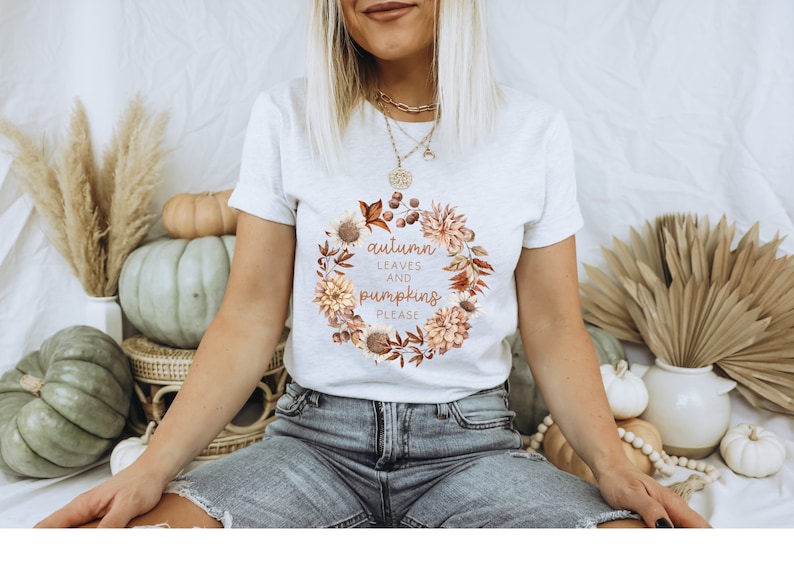 May include: White t-shirt with a floral wreath design and the text "autumn leaves and pumpkins please".