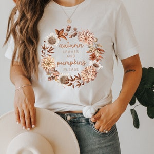 May include: White t-shirt with a floral wreath design and the text "autumn leaves and pumpkins please".