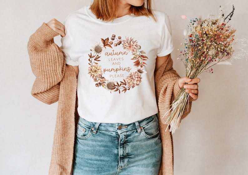 May include: White t-shirt with a floral wreath design and the text "autumn leaves and pumpkins please".